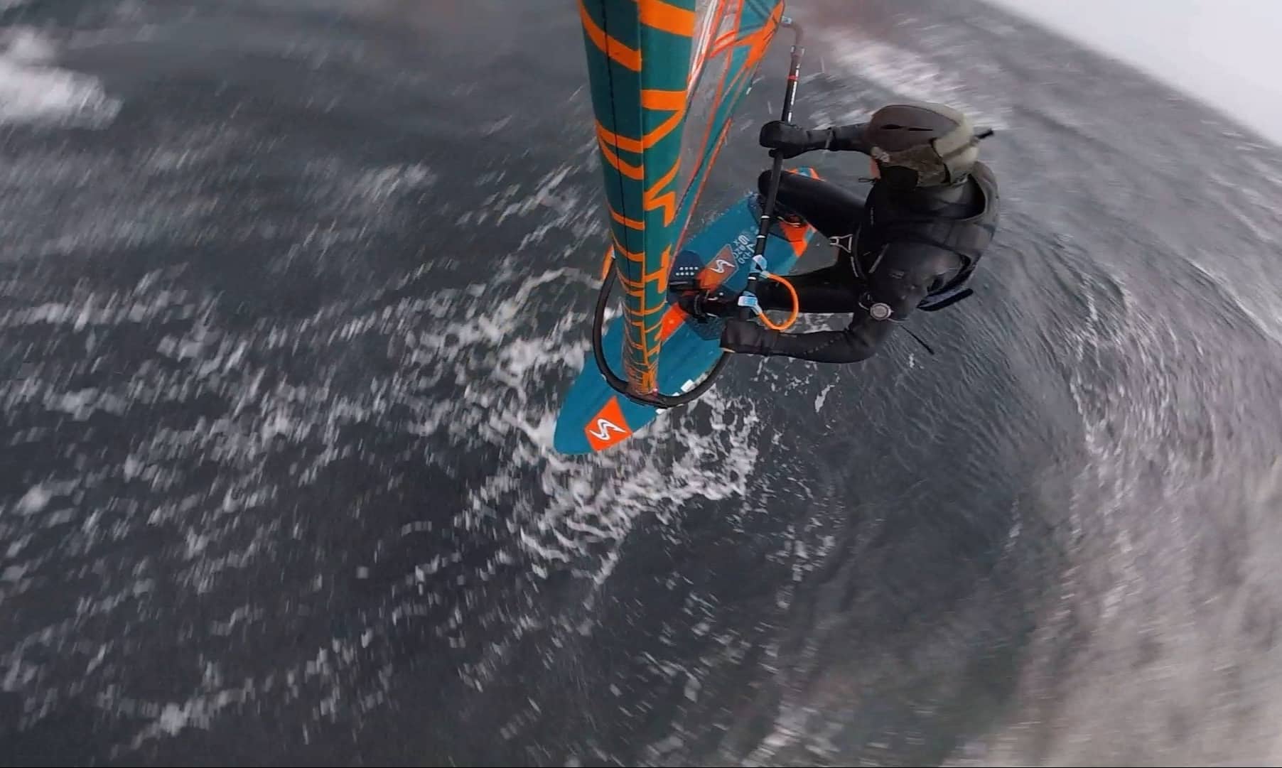 Windsurfer wearing the Sjø Protection soft surf helmet while doing an aerial rotation.