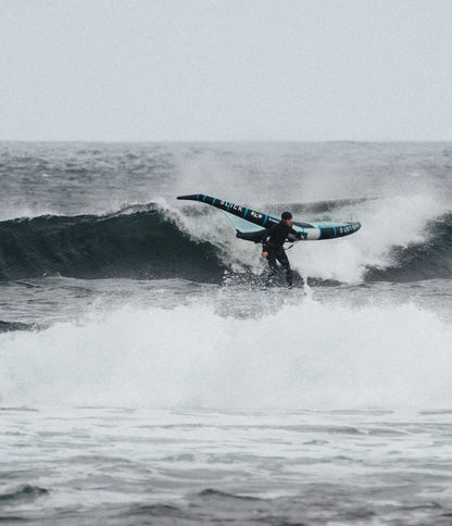 Wing foiler surfing a wave wearing the soft Kevlar reinforced surf helmet by Sjø Protection.