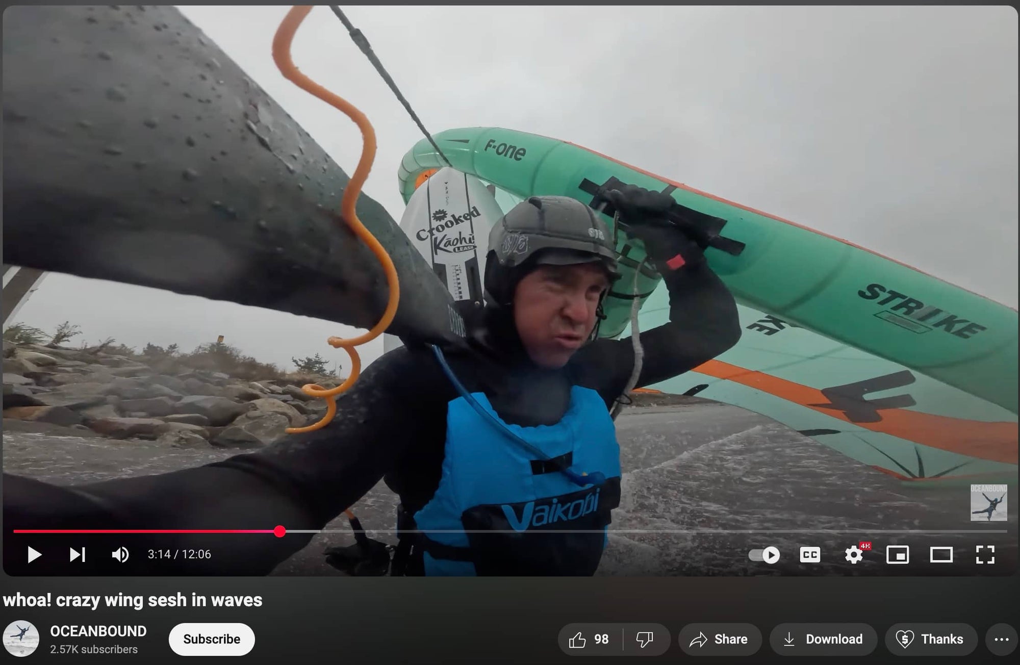 A youtuber is wearing the soft surf helmet by Sjø Protection while carrying his wingfoil gear out in the waves.